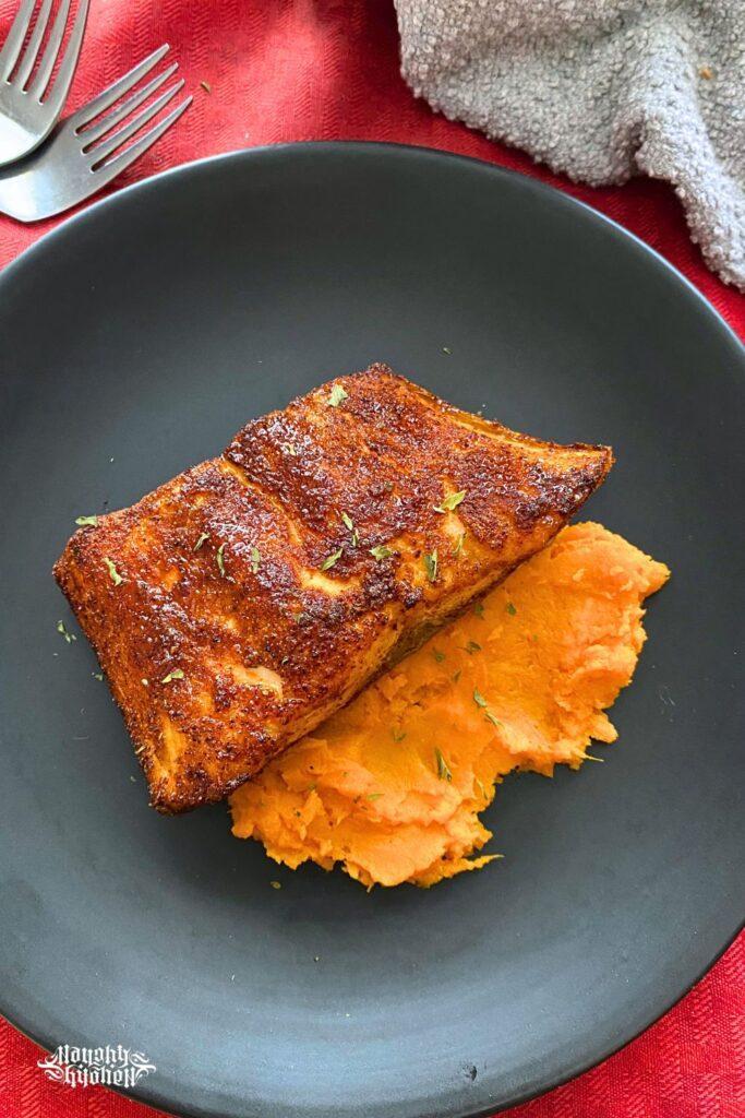 Broiled Maple Salmon with mashed sweet potatoes on a black plate.