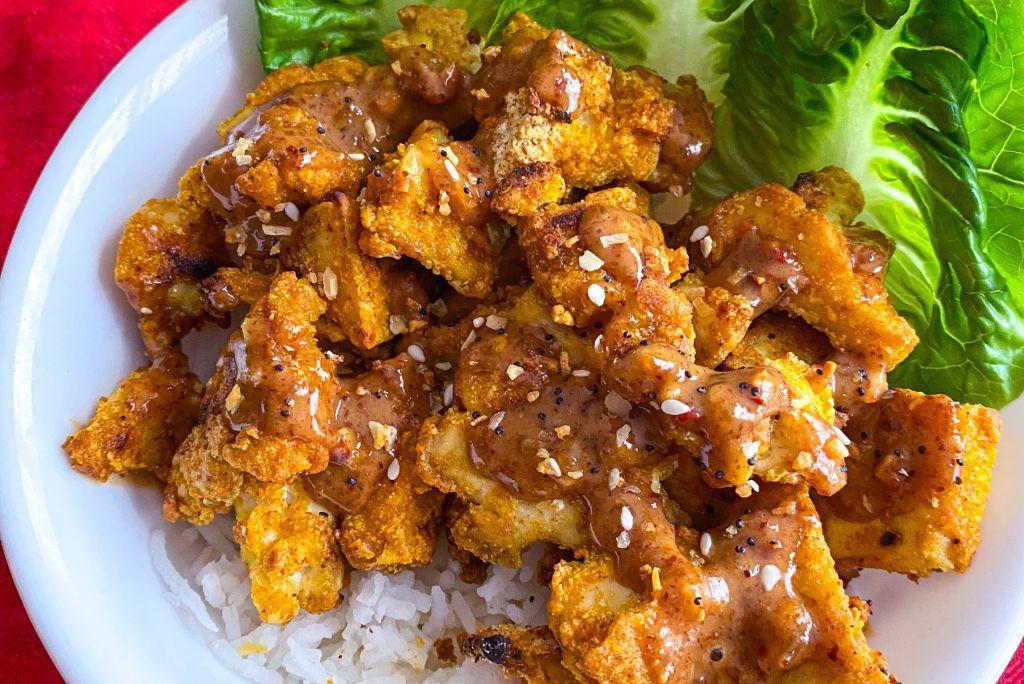 Almond Butter Tofu over rice and lettuce in a white bowl.