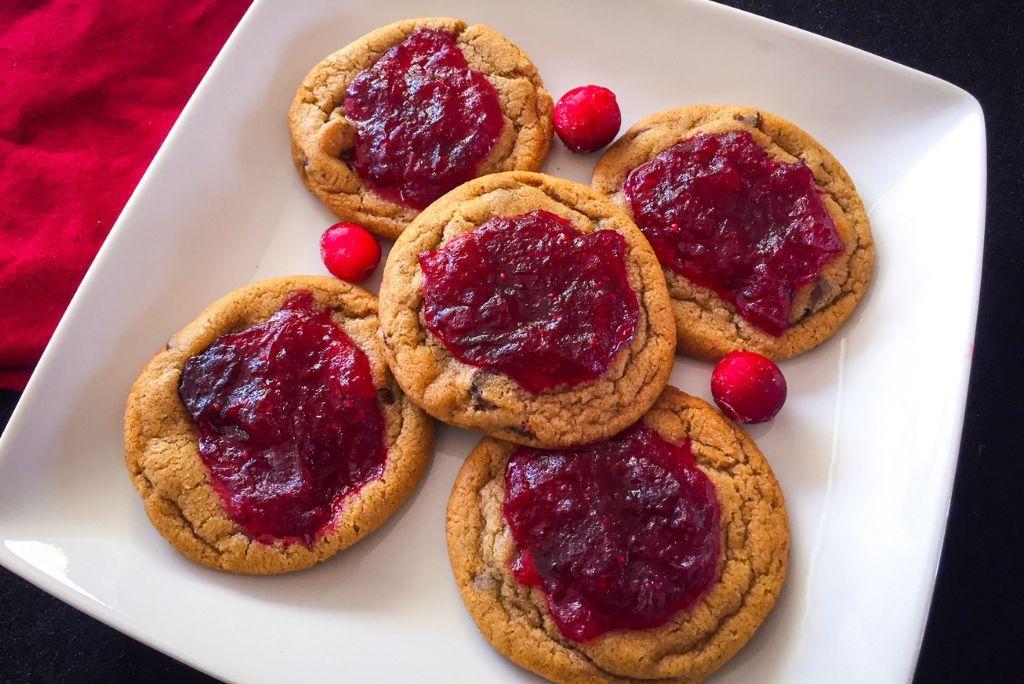 Cranberry jam chocolate chip cookies on a white plate with cranberries.