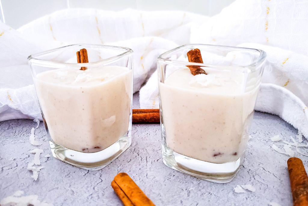 Coquito in shot glasses with cinnamon sticks.