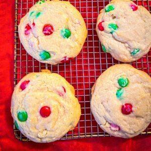 M&M Christmas Cookies on a cooling rack with red background.