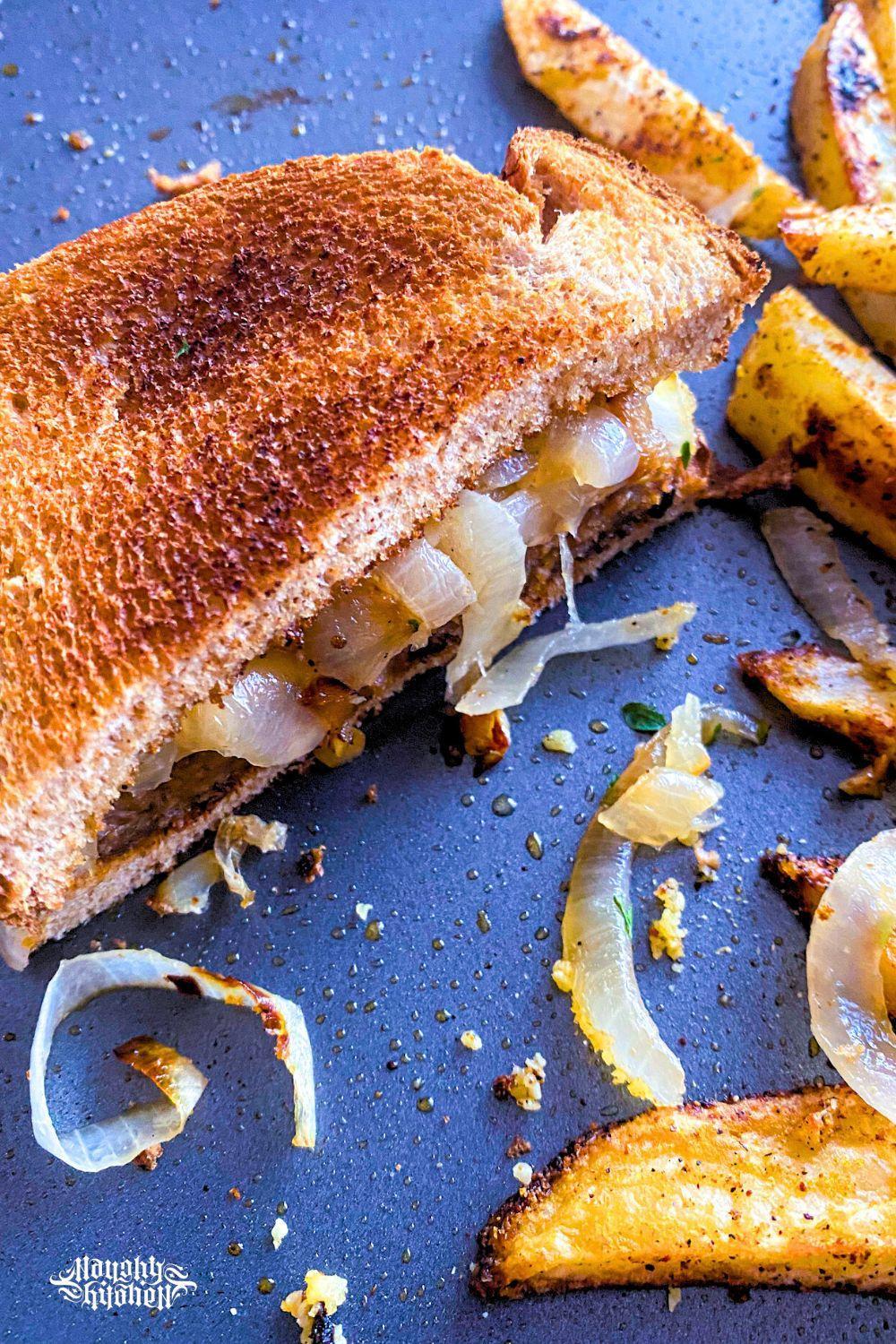 Half a slice of Vegan Patty Melt with potato wedges.