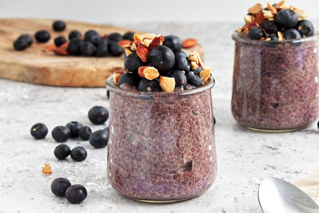 Two Blueberry Chia Puddings in jars with blueberries and almond toppings.