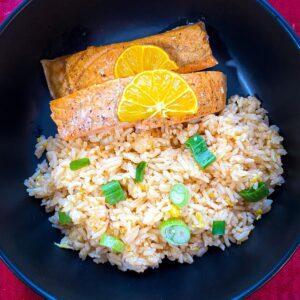 Calamansi Salmon with fried rice in a black bowl.