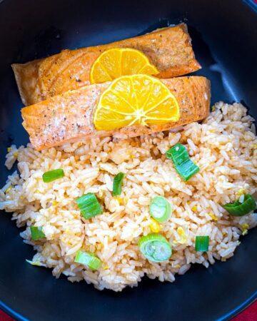 Calamansi Salmon with fried rice in a black bowl.