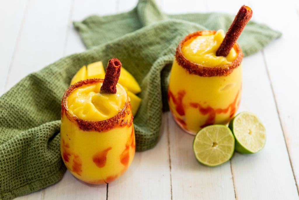 Two Mangonada with tamarind candy sticks on a table.