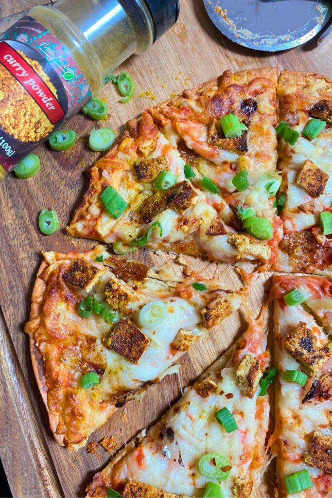 Tofu Curry Pizza with curry powder and pizza cutter.