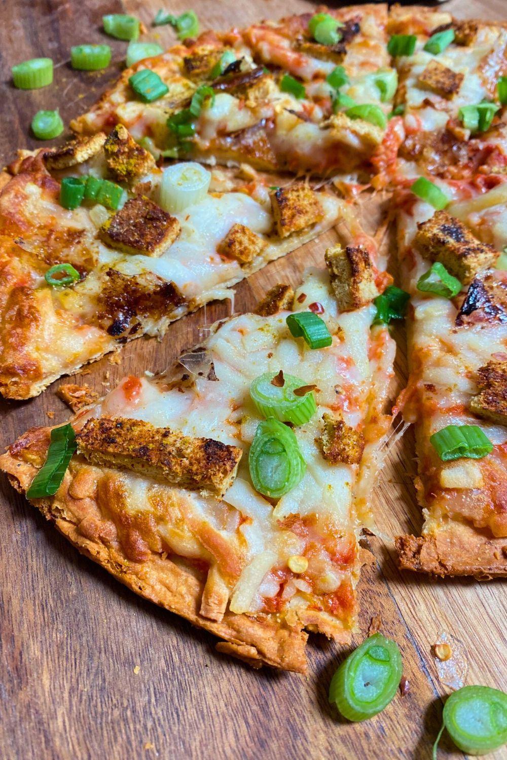 Tofu Curry Pizza slices with green onions on top.