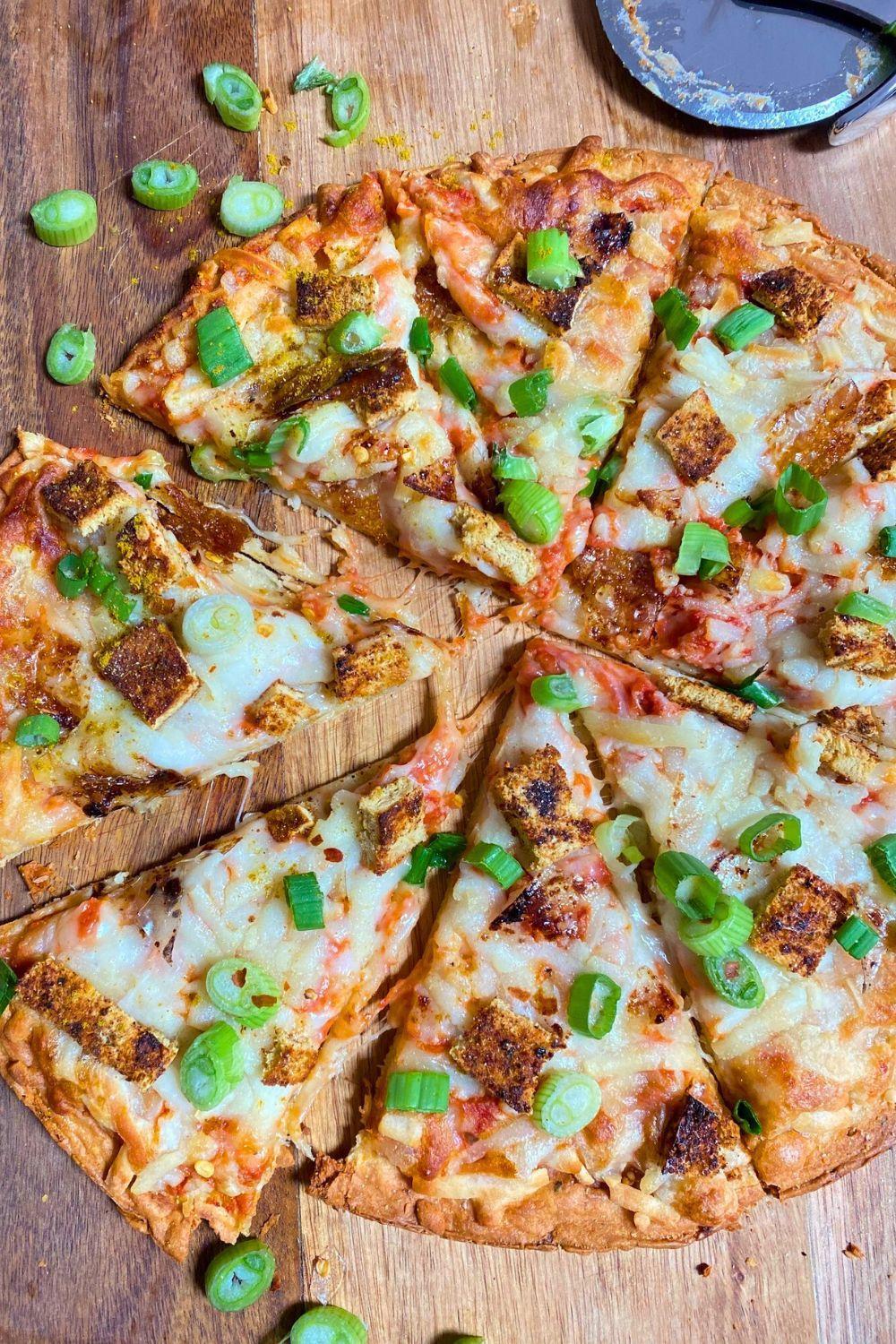 Tofu Curry Pizza slices overview with green onion toppings.