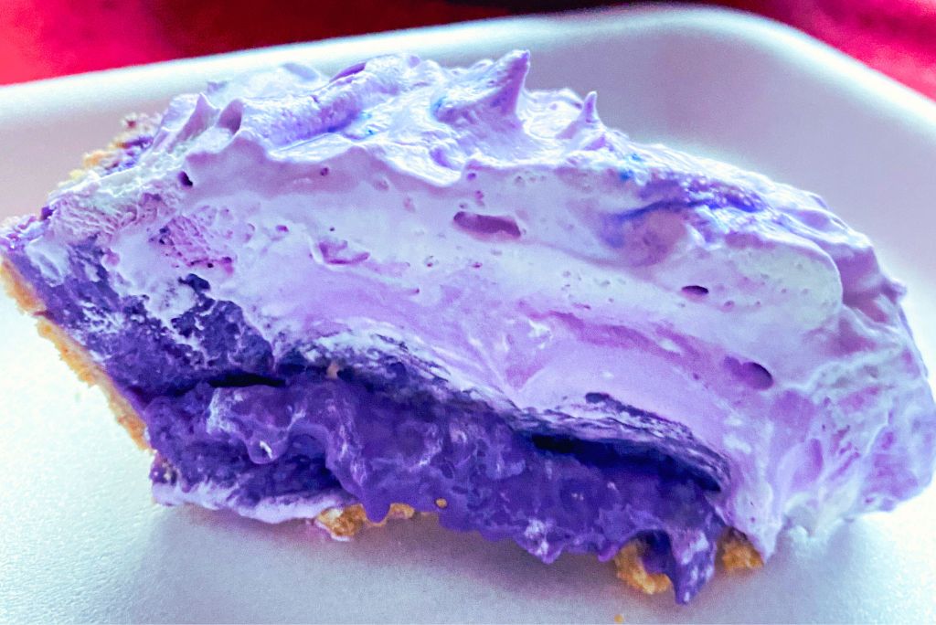 A slice of ube lush pudding pie on a white plate.