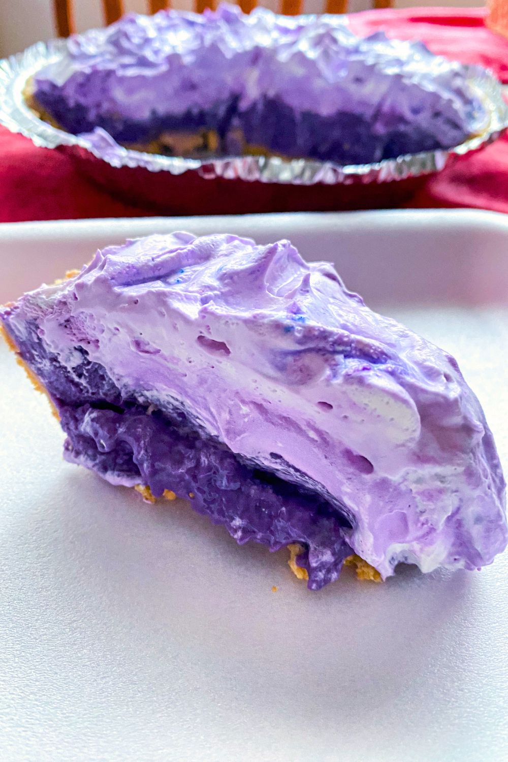 A slice of ube lush pudding pie with whole pie.