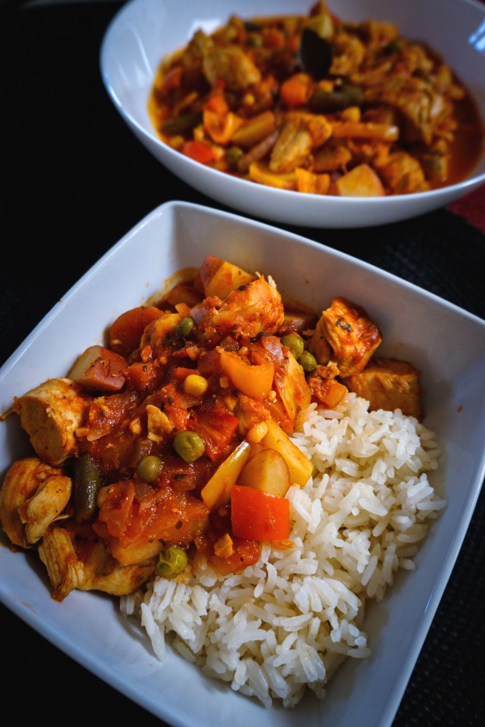 Chicken Afritada in a white bowl with rice.