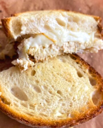 Golden brown air fryer sourdough tuna melt cut in half showing melted Muenster cheese and creamy tuna filling